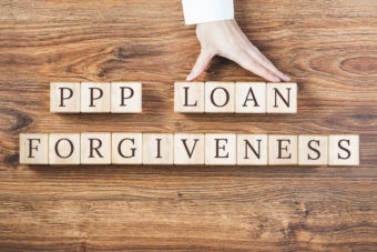 PPP LOAN Forgiveness text on wooden background, hand with percentage sign