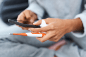 A woman holding a phone and a pen.