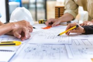 Employees looking at blueprints on a table.