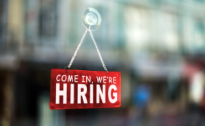 Sign on a window that reads "Come in, we're hiring."