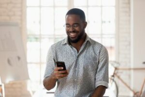 A man looking at his phone and smiling.