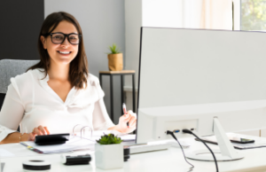 A woman working at her computer and smiling.