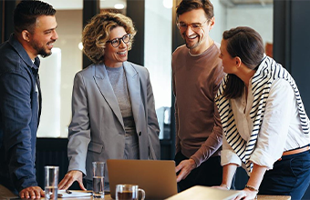 Four employees looking at benefits on a laptop.