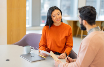 Two coworkers conversing at conference table