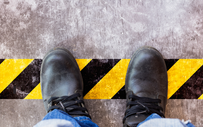 Employee standing on hazard tape on factory floor