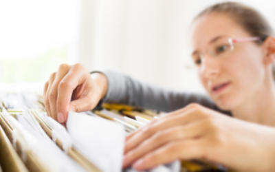Woman searching for a file in a drawer full of files.