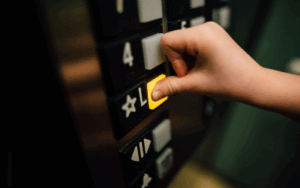 Elevator buttons with person's thumb pressing the Lobby button