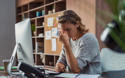 Woman behind her desk resting her face on one hand showing fatigue