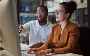Manager training employee on computer