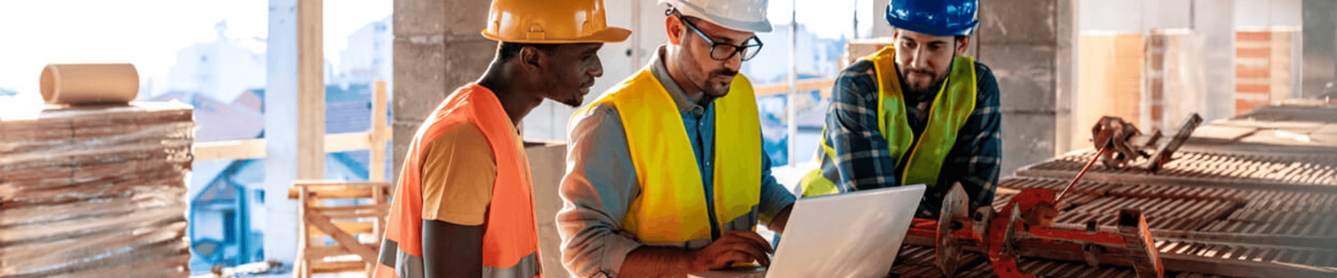 Three construction workers reviewing plans in an in progress building.