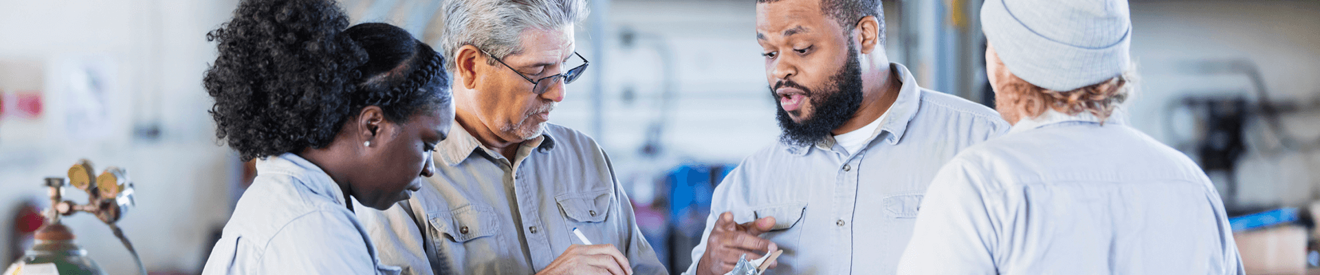 Four industrial workers discussing and reviewing in a factory.