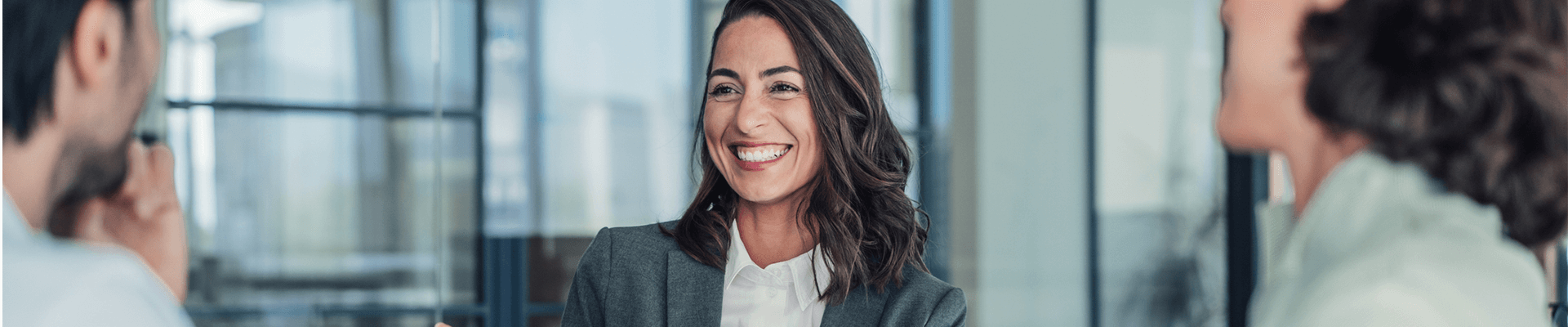 Professional woman smiling and talking to co workers in an office presentation room.