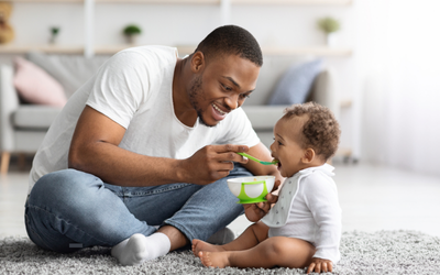 Dad caring for toddler, feeding him.