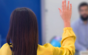 Woman raising hand representing the Learn & Grow product