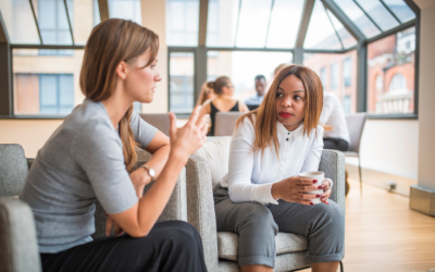 Two women in workplace talking to each other.