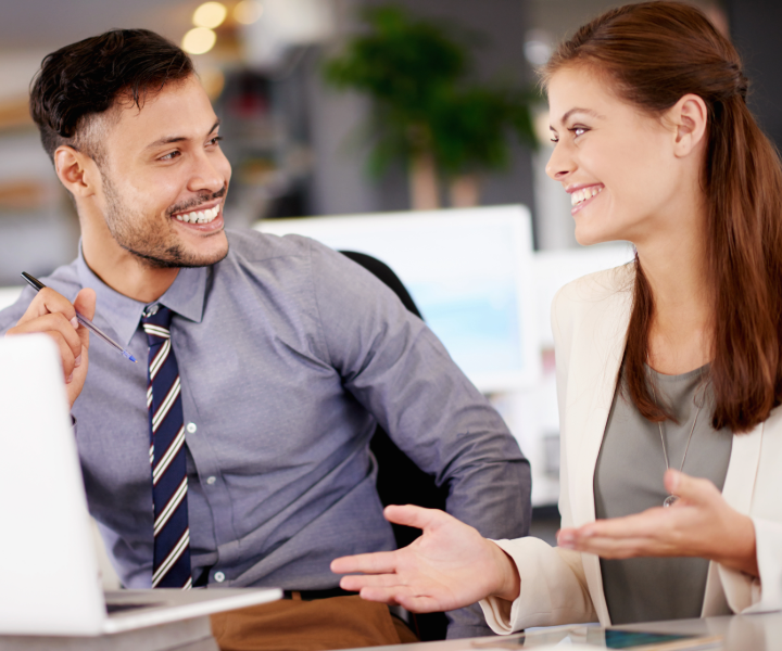 Two co-workers (man and woman) smiling at each other