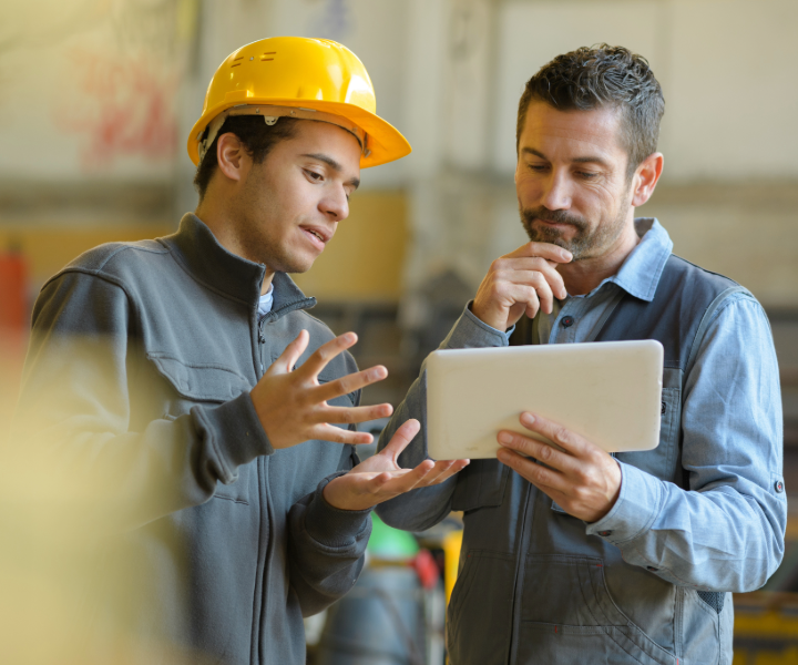 Two co-workers in the construction industry analyzing information on a tablet together.