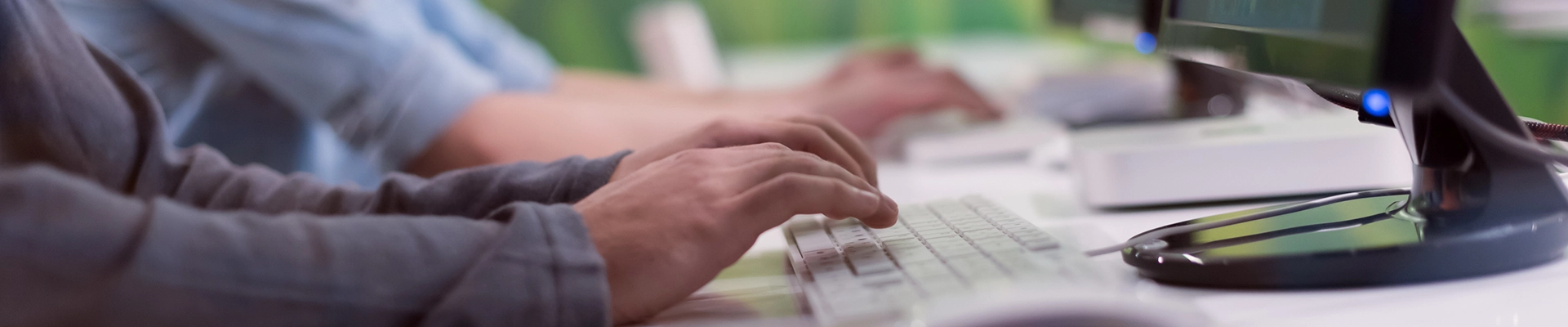Hands typing at computer keyboard