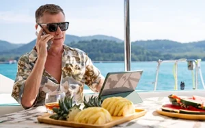 Man on laptop and mobile phone while on vacation - "Why Aren’t Employees Taking the PTO They’ve Earned?"