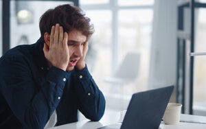 man sitting at laptop looking concerned - employee post goes viral