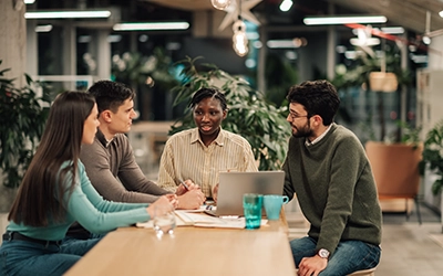 Diverse business team collaborating around table with laptop